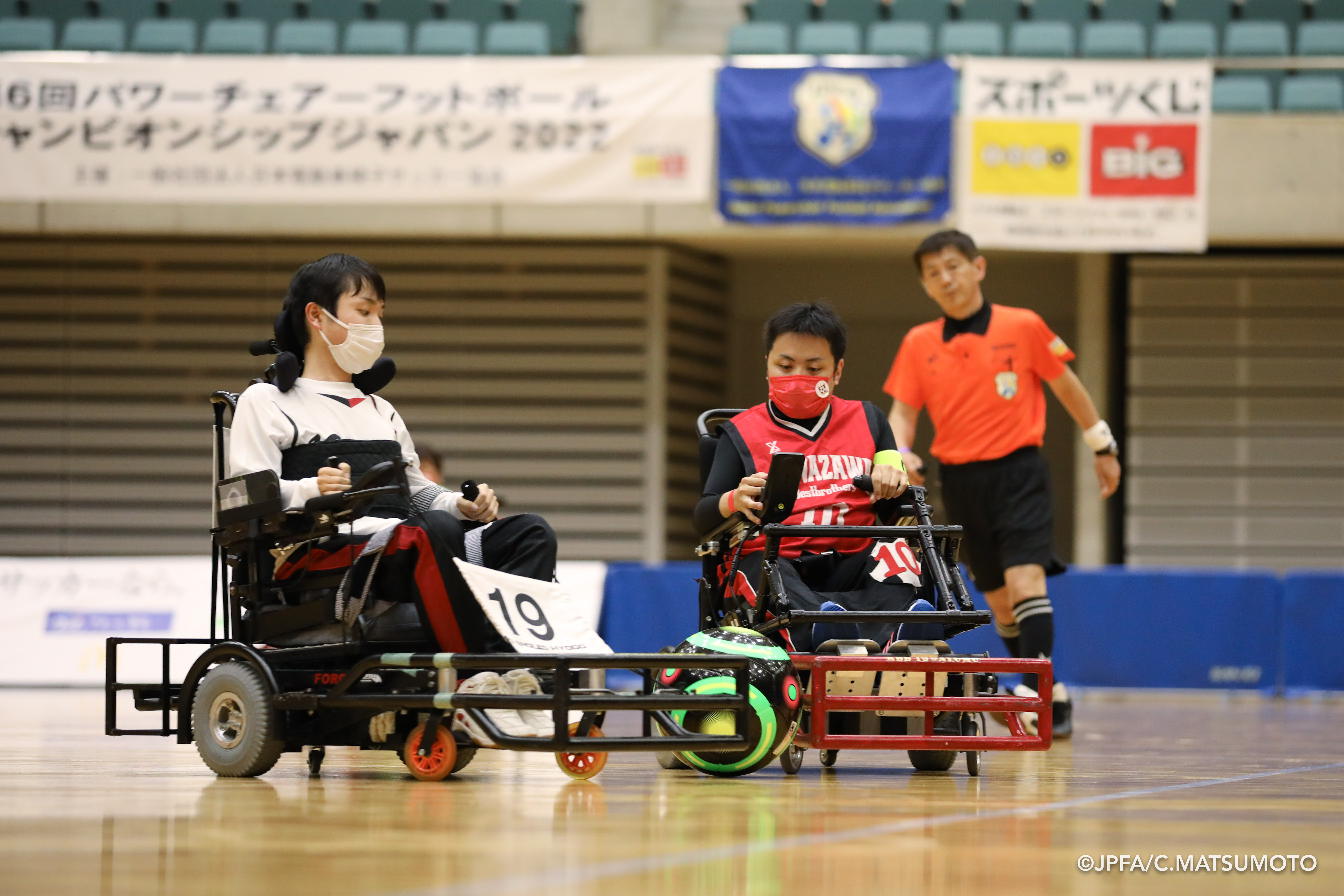 電動車椅子サッカーの選手2人がボールを取り合っている