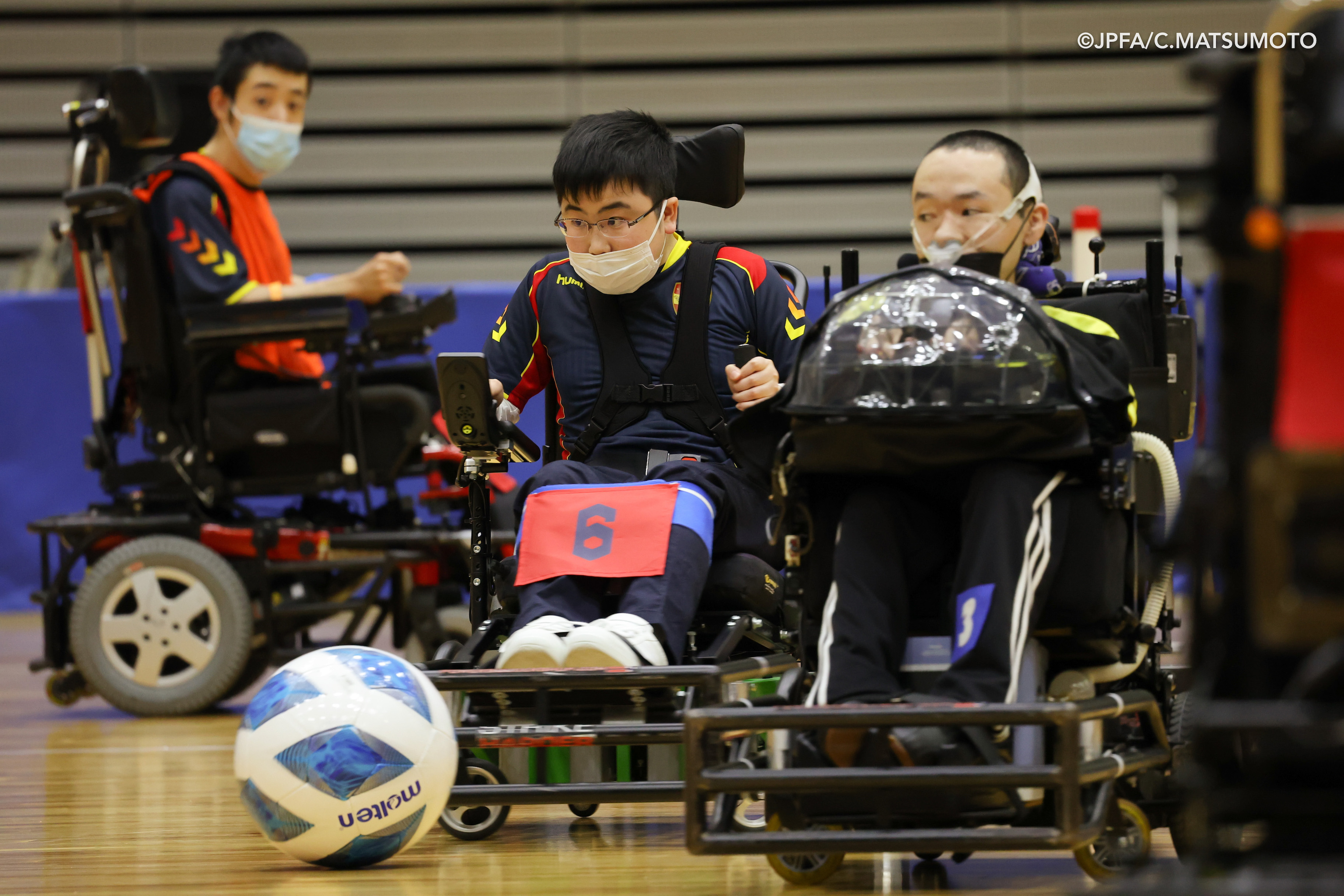 電動車椅子サッカーの選手2人がボールを取り合っている